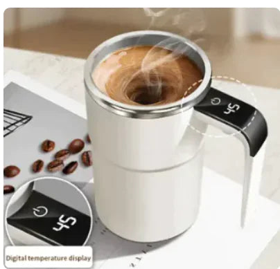 Stainless steel coffee cup with steam wand on a surface with coffee beans and a blurred background.